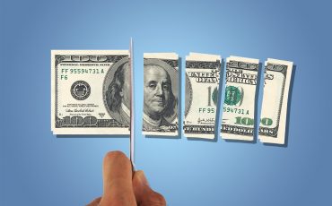 Front view of one hundred dollar banknotes, slicing with a knife on hand, isolated on white background.